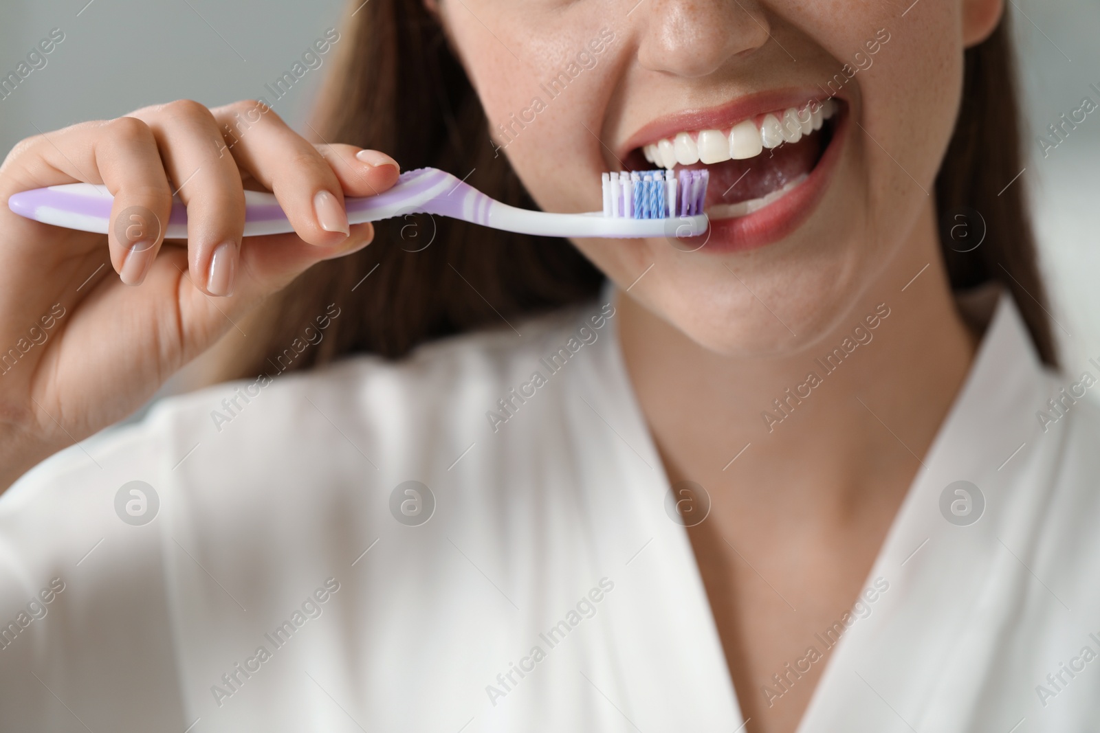 Photo of Woman brushing her teeth in bathroom, closeup