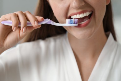 Photo of Woman brushing her teeth in bathroom, closeup