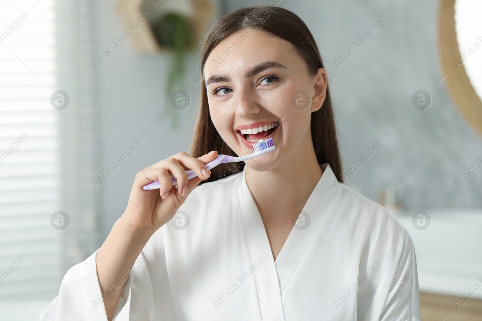 Photo of Beautiful woman brushing her teeth in bathroom