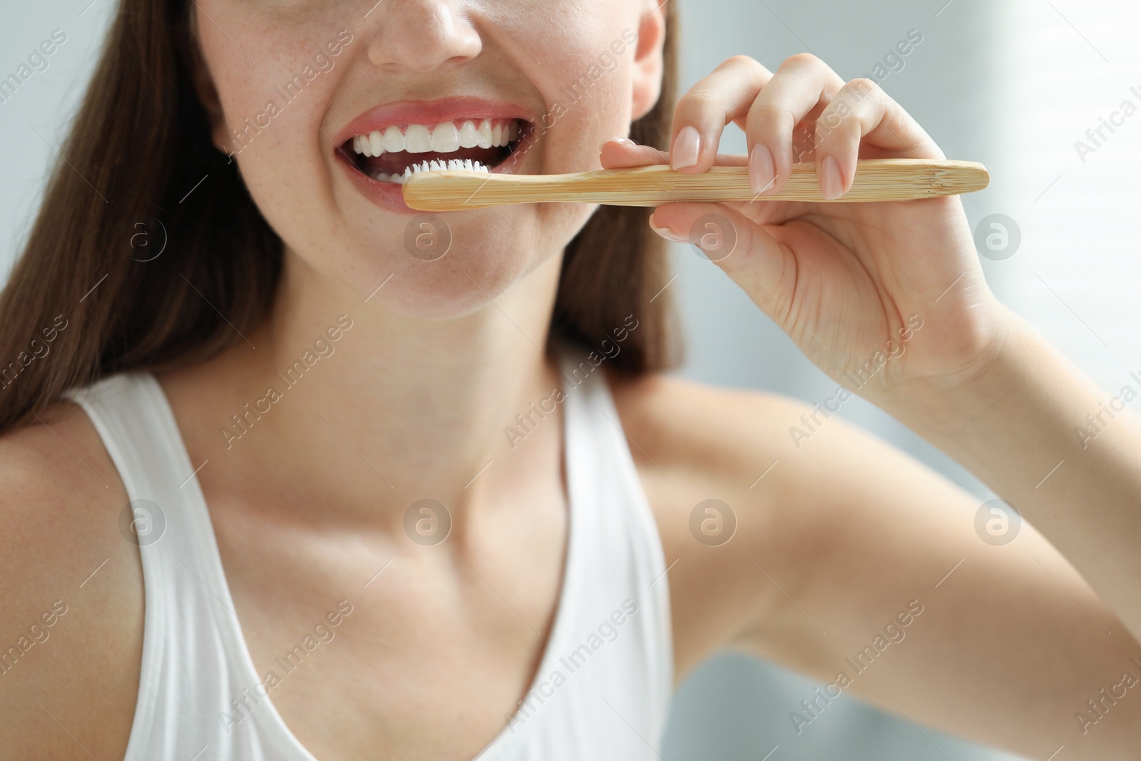 Photo of Woman brushing her teeth in bathroom, closeup