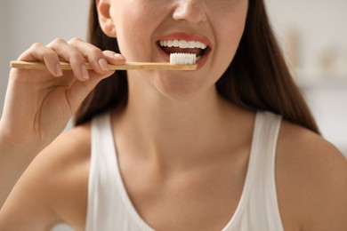 Photo of Woman brushing her teeth in bathroom, closeup