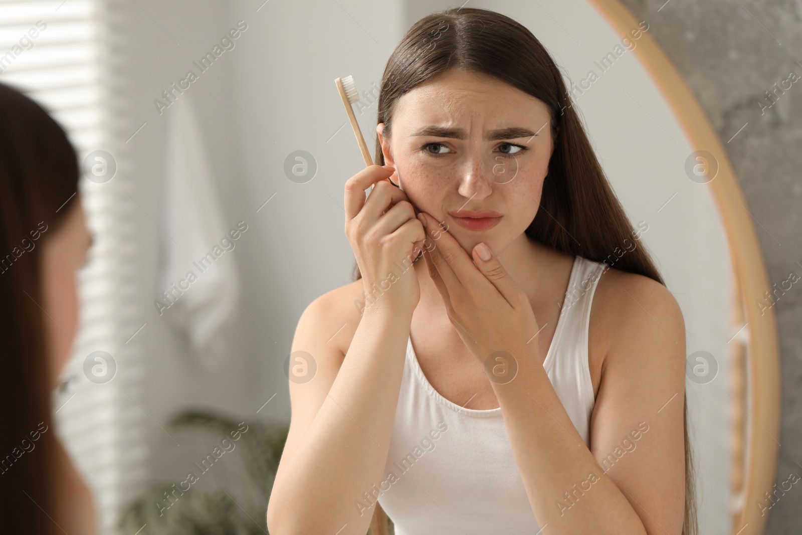 Photo of Young woman with toothbrush suffering from toothache in bathroom