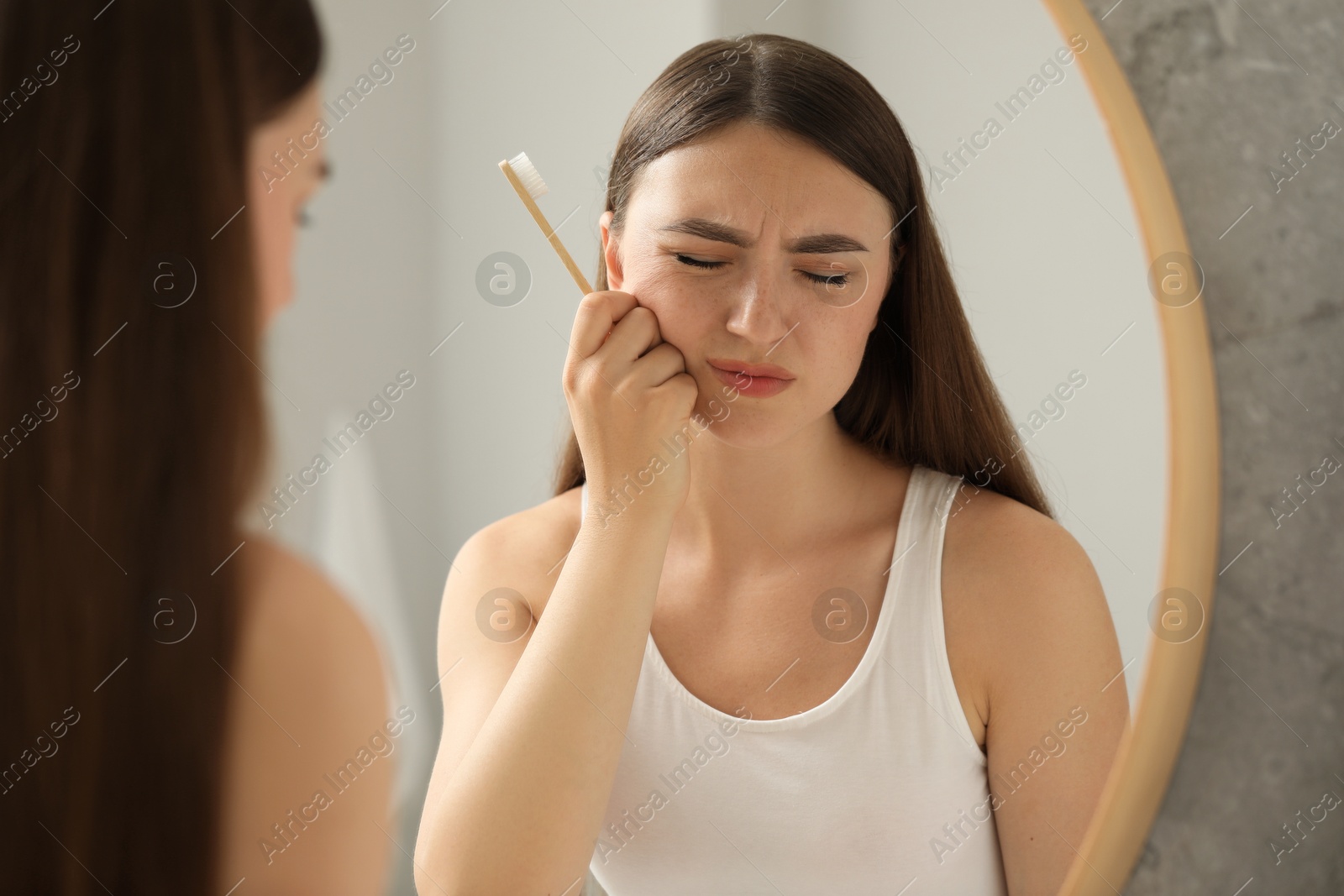 Photo of Young woman with toothbrush suffering from toothache in bathroom