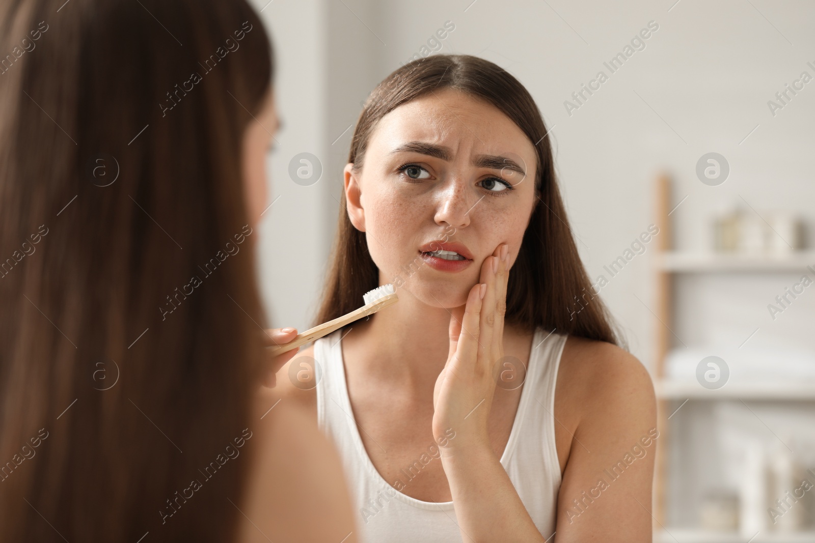 Photo of Young woman with toothbrush suffering from toothache in bathroom