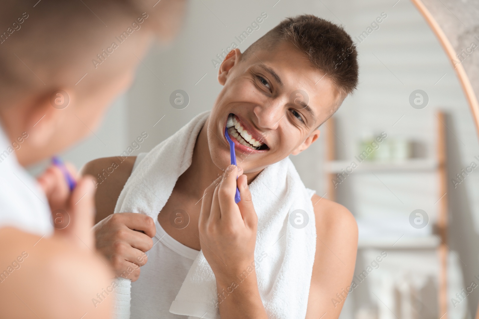 Photo of Young man brushing his teeth in bathroom