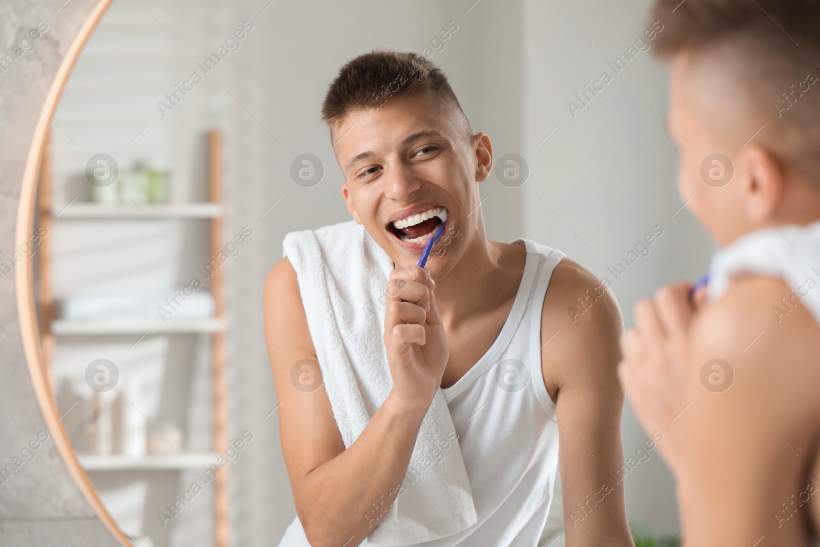 Photo of Young man brushing his teeth in bathroom