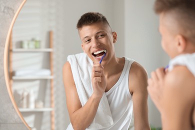 Young man brushing his teeth in bathroom