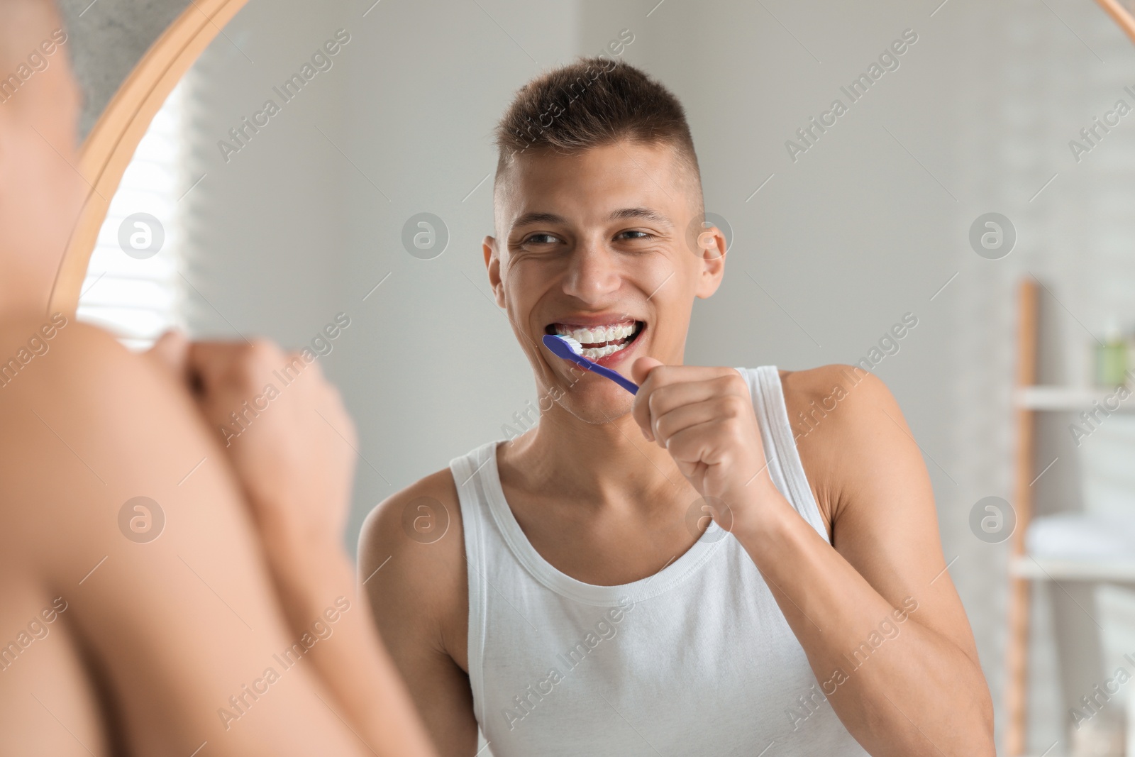 Photo of Young man brushing his teeth in bathroom