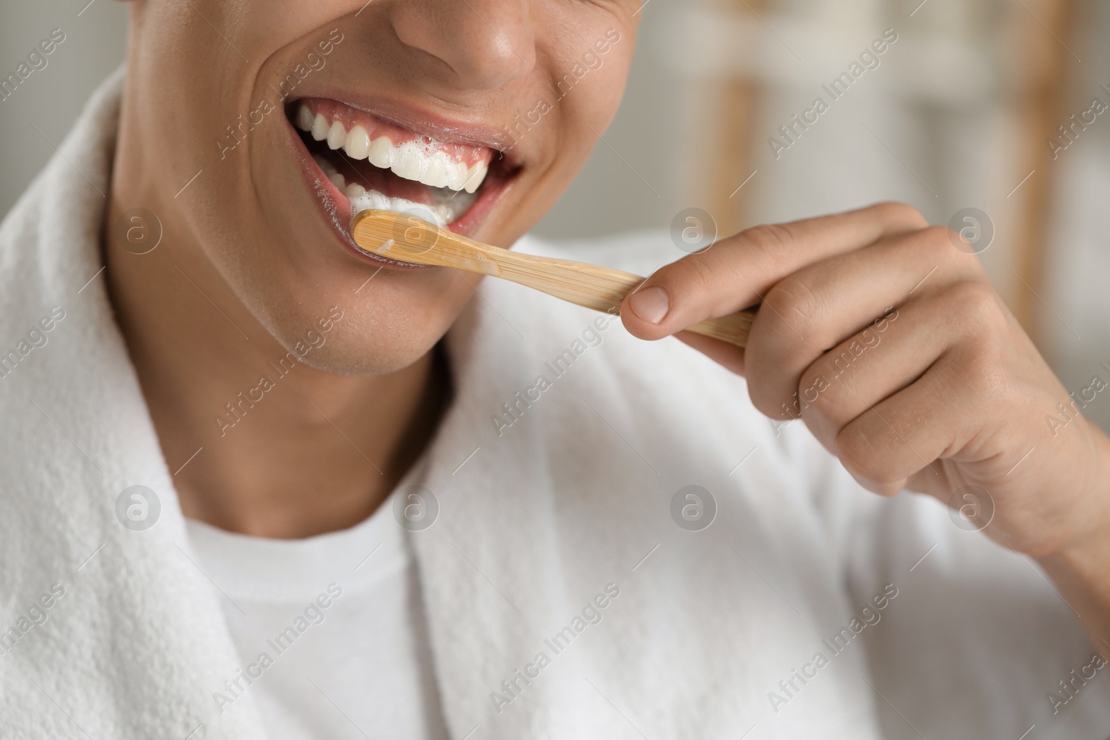 Photo of Young man brushing his teeth in bathroom, closeup