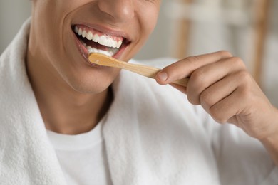 Young man brushing his teeth in bathroom, closeup