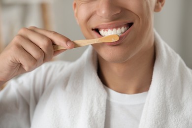 Photo of Young man brushing his teeth in bathroom, closeup