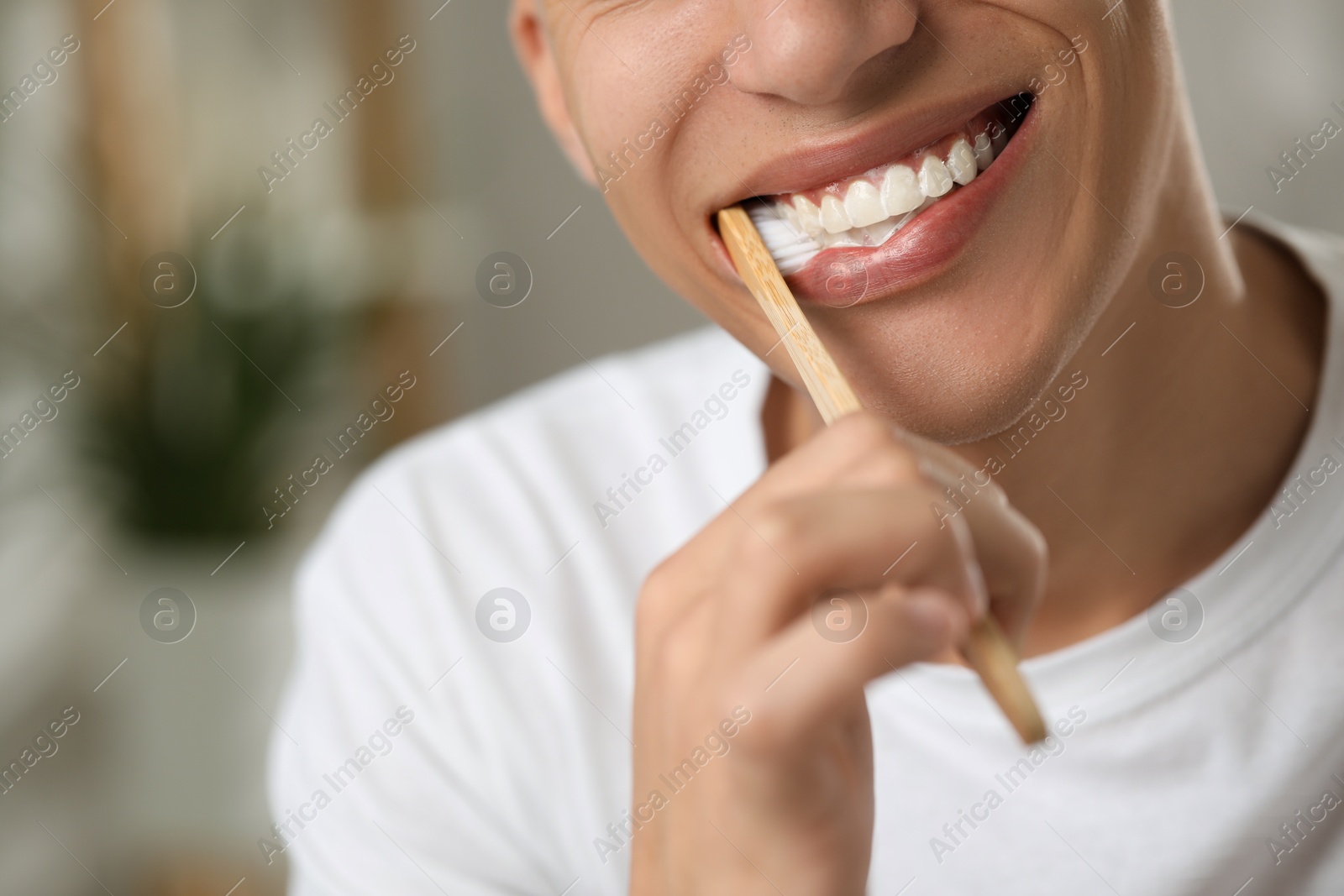 Photo of Young man brushing his teeth in bathroom, closeup