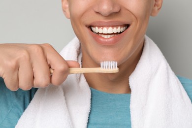 Photo of Young man brushing his teeth on gray background, closeup