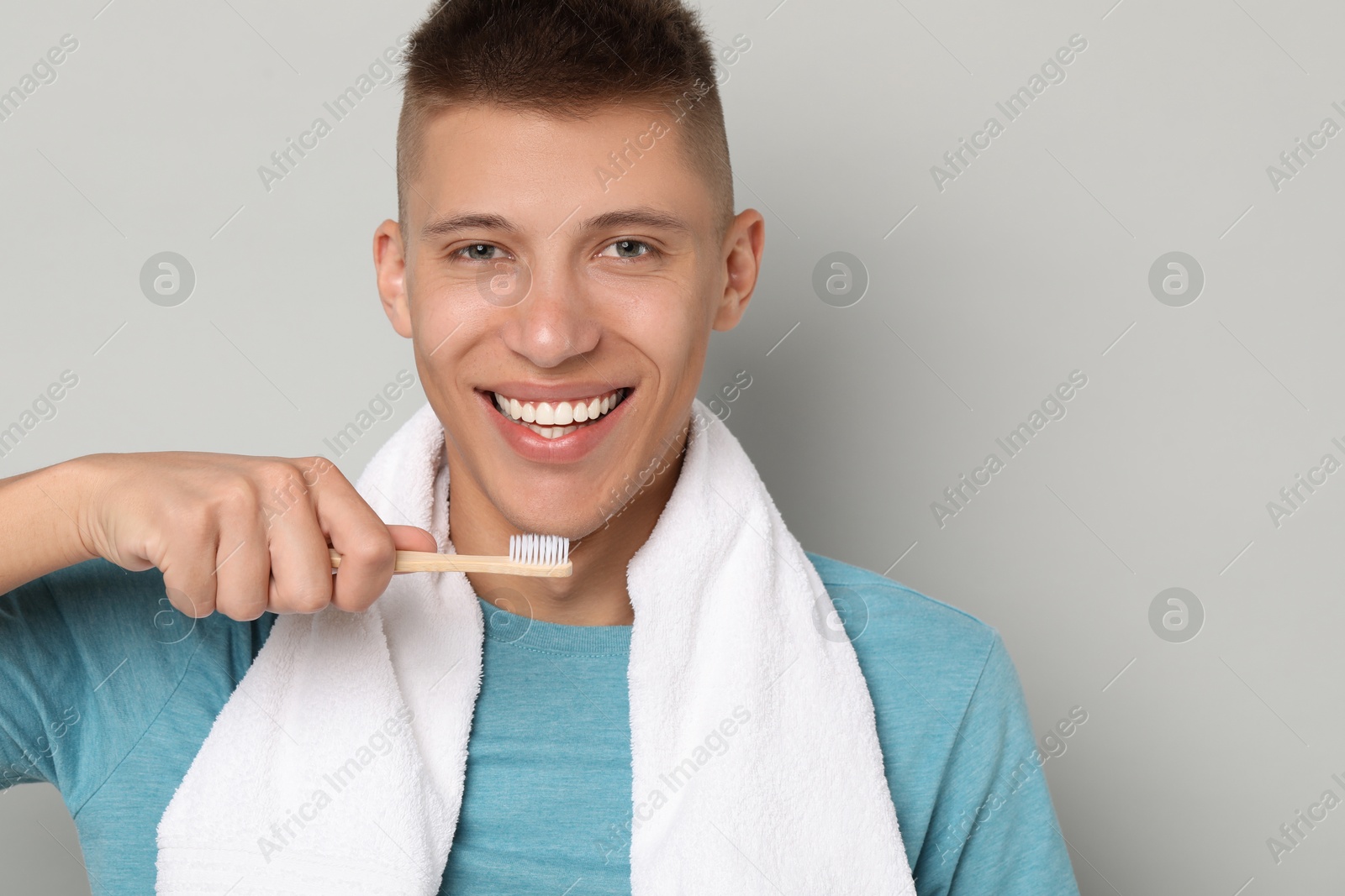 Photo of Young man brushing his teeth on gray background