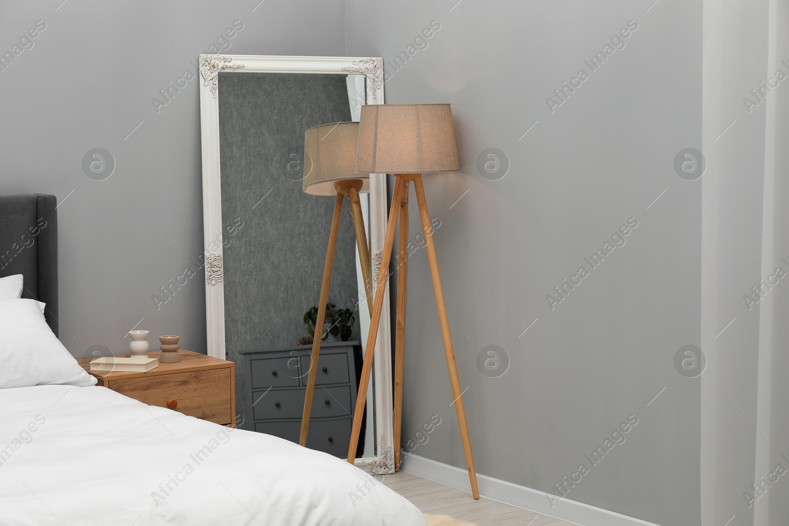 Photo of Large mirror near grey wall in bedroom. Interior design