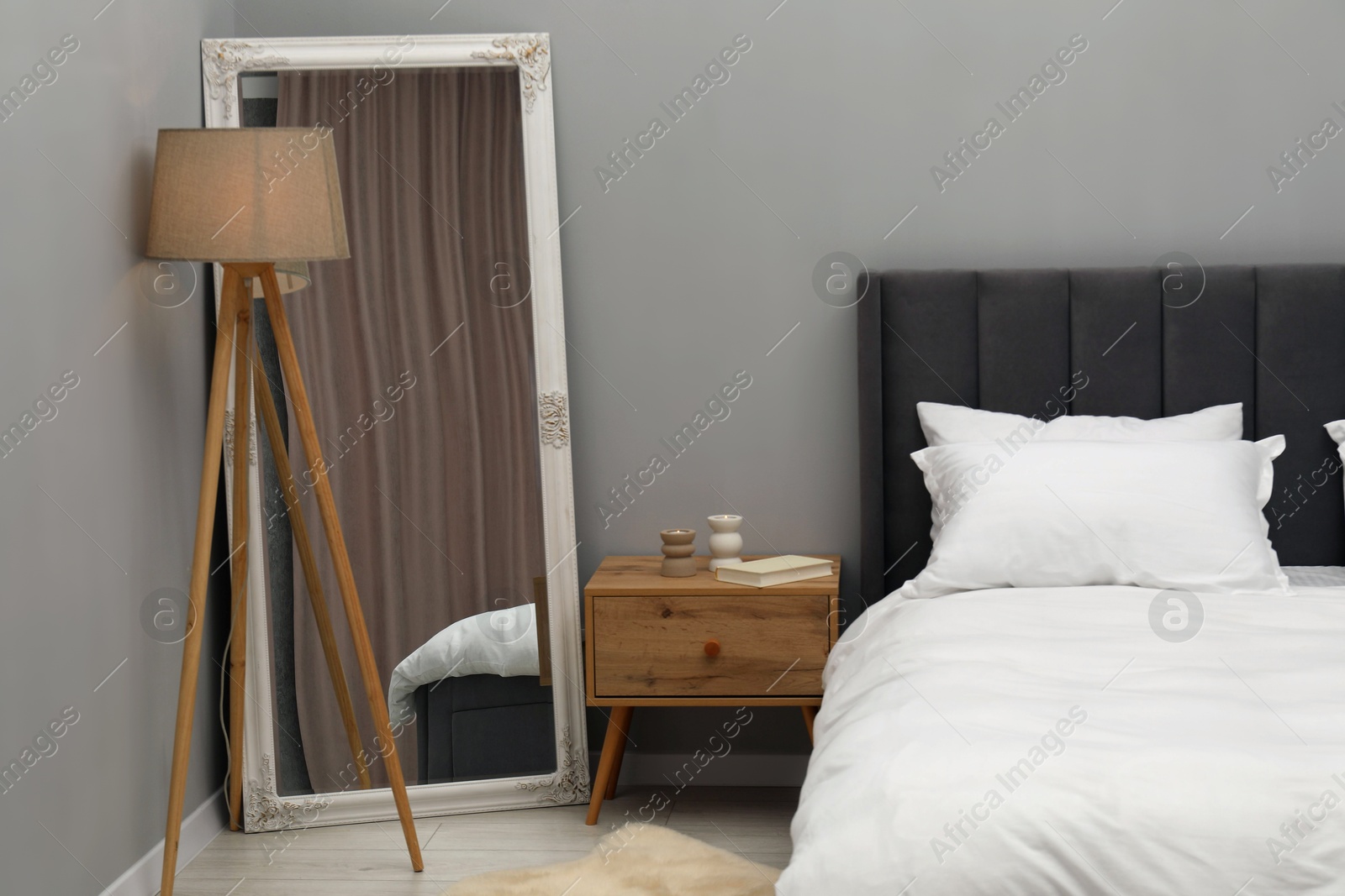 Photo of Large mirror near grey wall in bedroom. Interior design