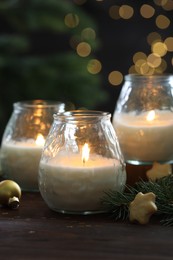 Photo of Burning candles, baubles and fir tree branches on wooden table, closeup