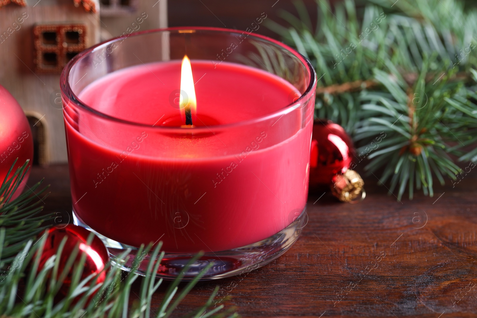 Photo of Burning candle, Christmas decor and fir tree branches on wooden table, closeup