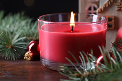 Photo of Burning candle, Christmas decor and fir tree branches on wooden table, closeup