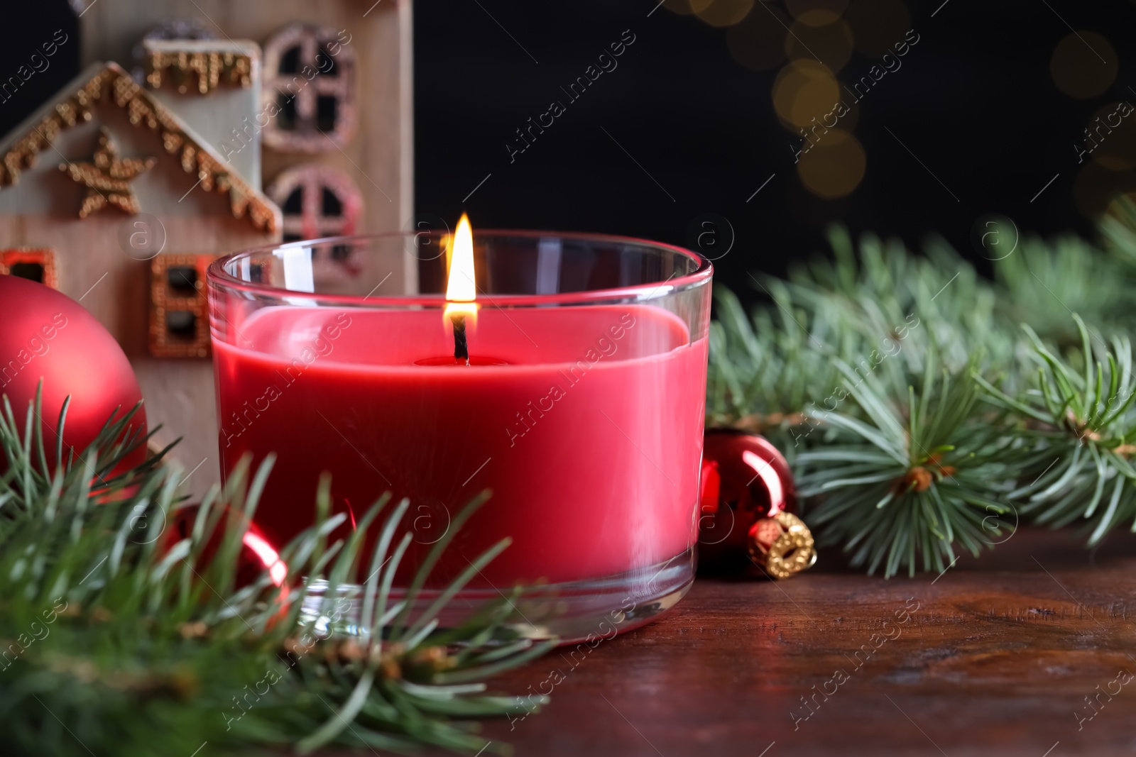 Photo of Burning candle, Christmas decor and fir tree branches on wooden table, closeup