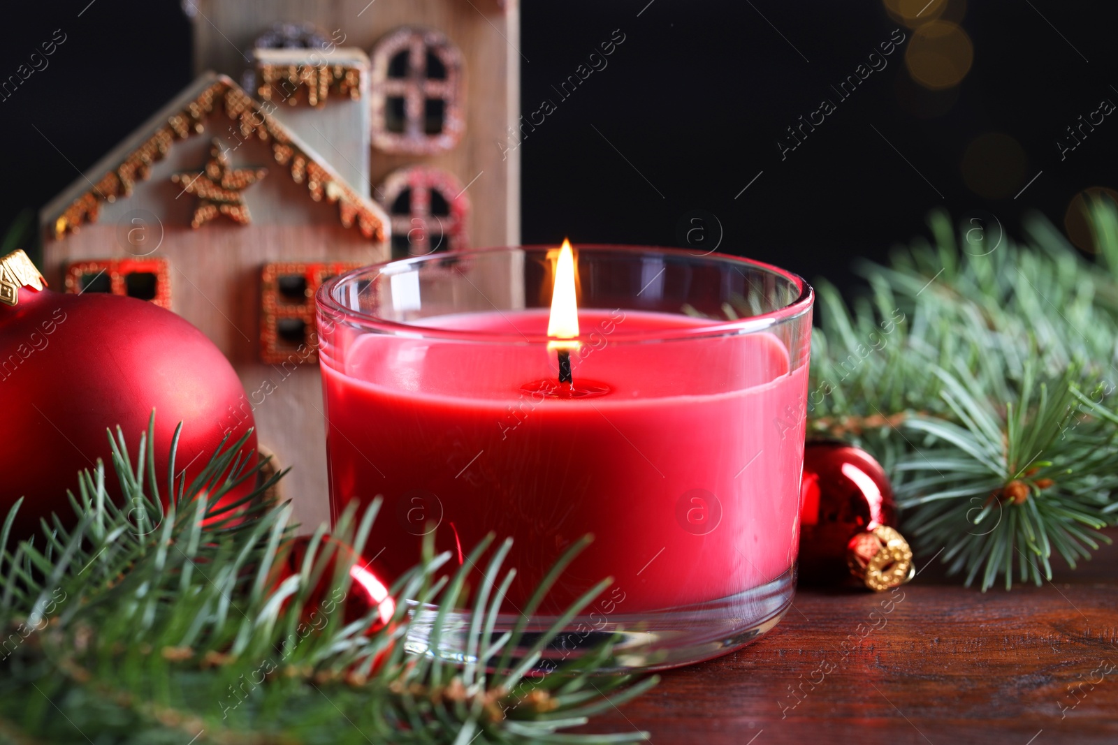 Photo of Burning candle, Christmas decor and fir tree branches on wooden table, closeup