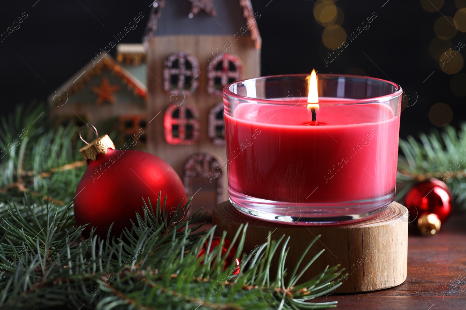 Photo of Burning candle, Christmas decor and fir tree branches on wooden table, closeup