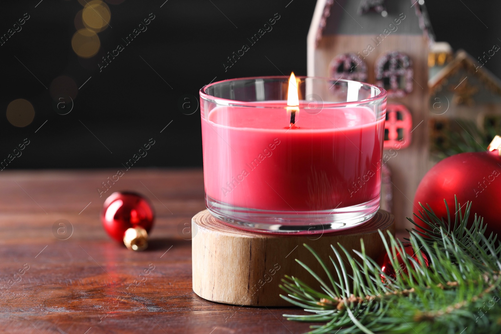 Photo of Burning candle, Christmas decor and fir tree branches on wooden table, closeup. Space for text