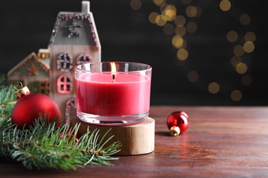 Photo of Burning candle, Christmas decor and fir tree branches on wooden table, closeup. Space for text