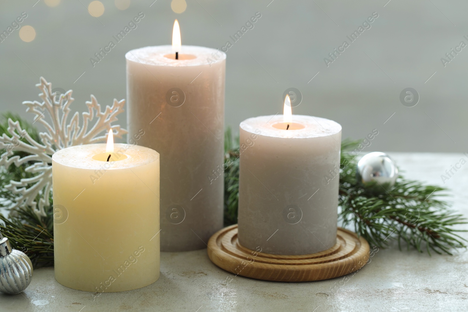 Photo of Burning candles, baubles and fir tree branches on white textured table, closeup