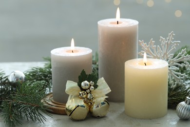 Photo of Burning candles, baubles and fir tree branches on white textured table, closeup