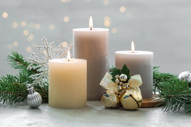 Photo of Burning candles, baubles and fir tree branches on white textured table, closeup