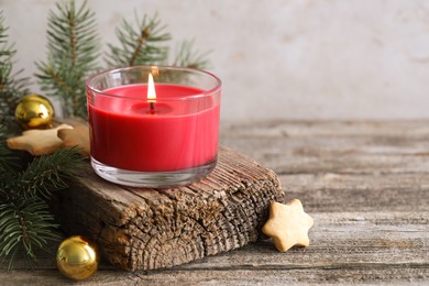 Photo of Burning candle, baubles, Christmas cookies and fir tree branches on wooden table, closeup. Space for text