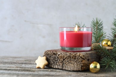 Photo of Burning candle, baubles, Christmas cookies and fir tree branches on wooden table, closeup. Space for text