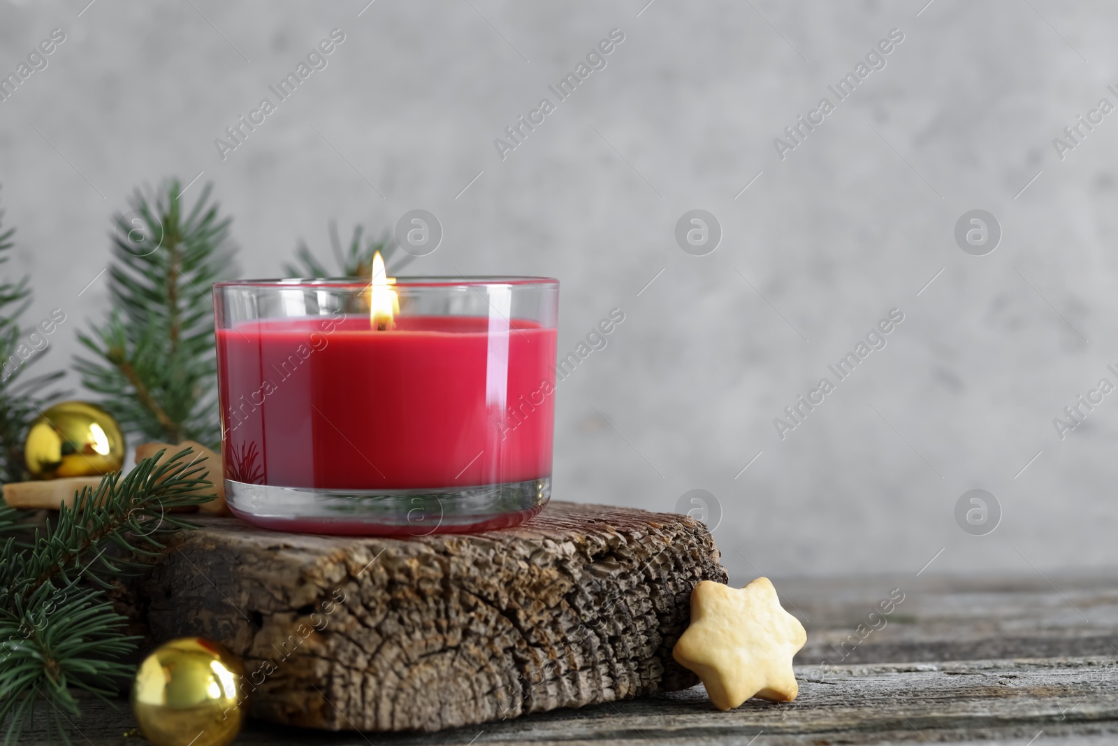 Photo of Burning candle, baubles, Christmas cookies and fir tree branches on wooden table, closeup. Space for text