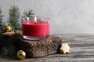 Photo of Burning candle, baubles, Christmas cookies and fir tree branches on wooden table, closeup. Space for text