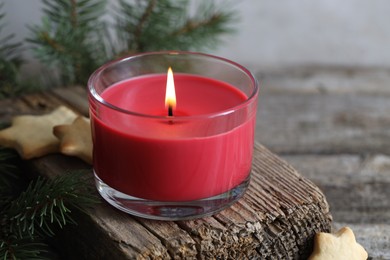 Photo of Burning candle, Christmas cookies and fir tree branches on wooden table, closeup