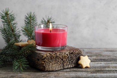 Photo of Burning candle, Christmas cookies and fir tree branches on wooden table, closeup. Space for text