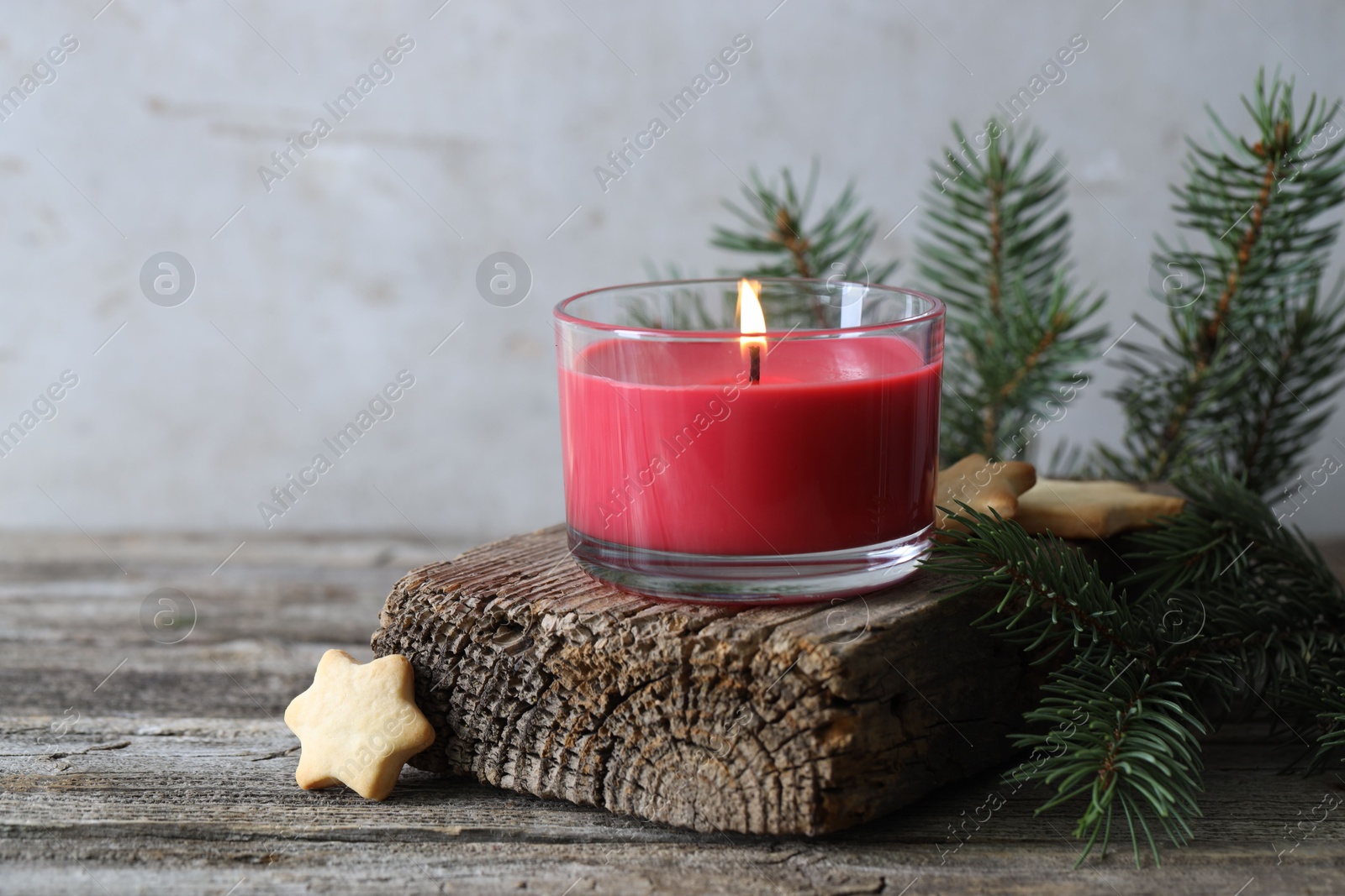 Photo of Burning candle, Christmas cookies and fir tree branches on wooden table, closeup. Space for text