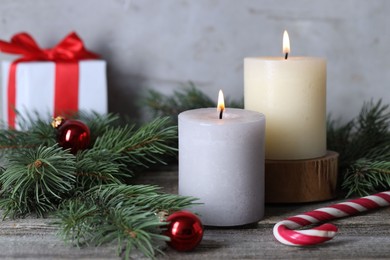 Photo of Burning candles, Christmas decor and fir tree branches on wooden table, closeup