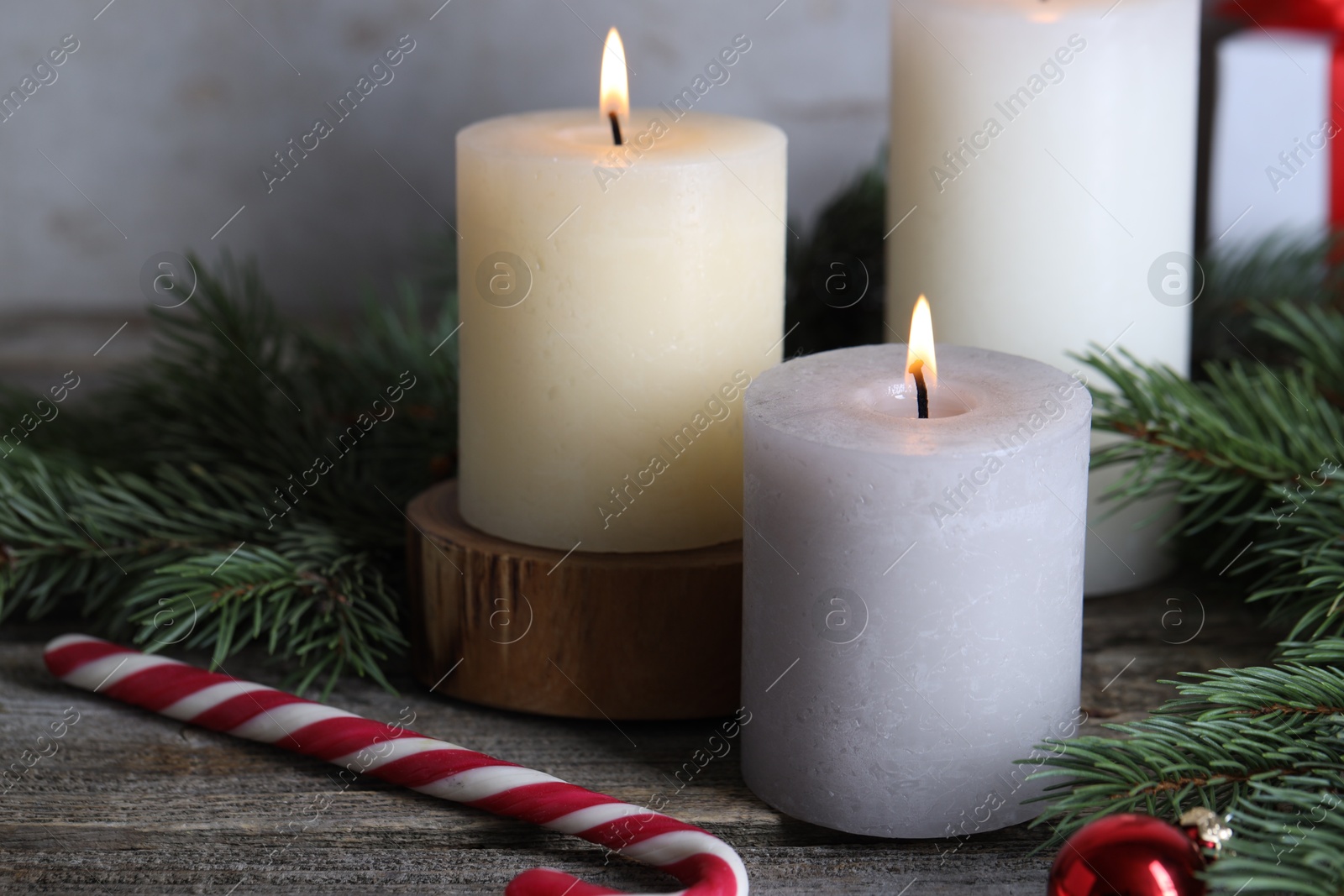 Photo of Burning candles, Christmas decor and fir tree branches on wooden table, closeup