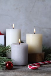 Photo of Burning candles, Christmas decor and fir tree branches on wooden table, closeup