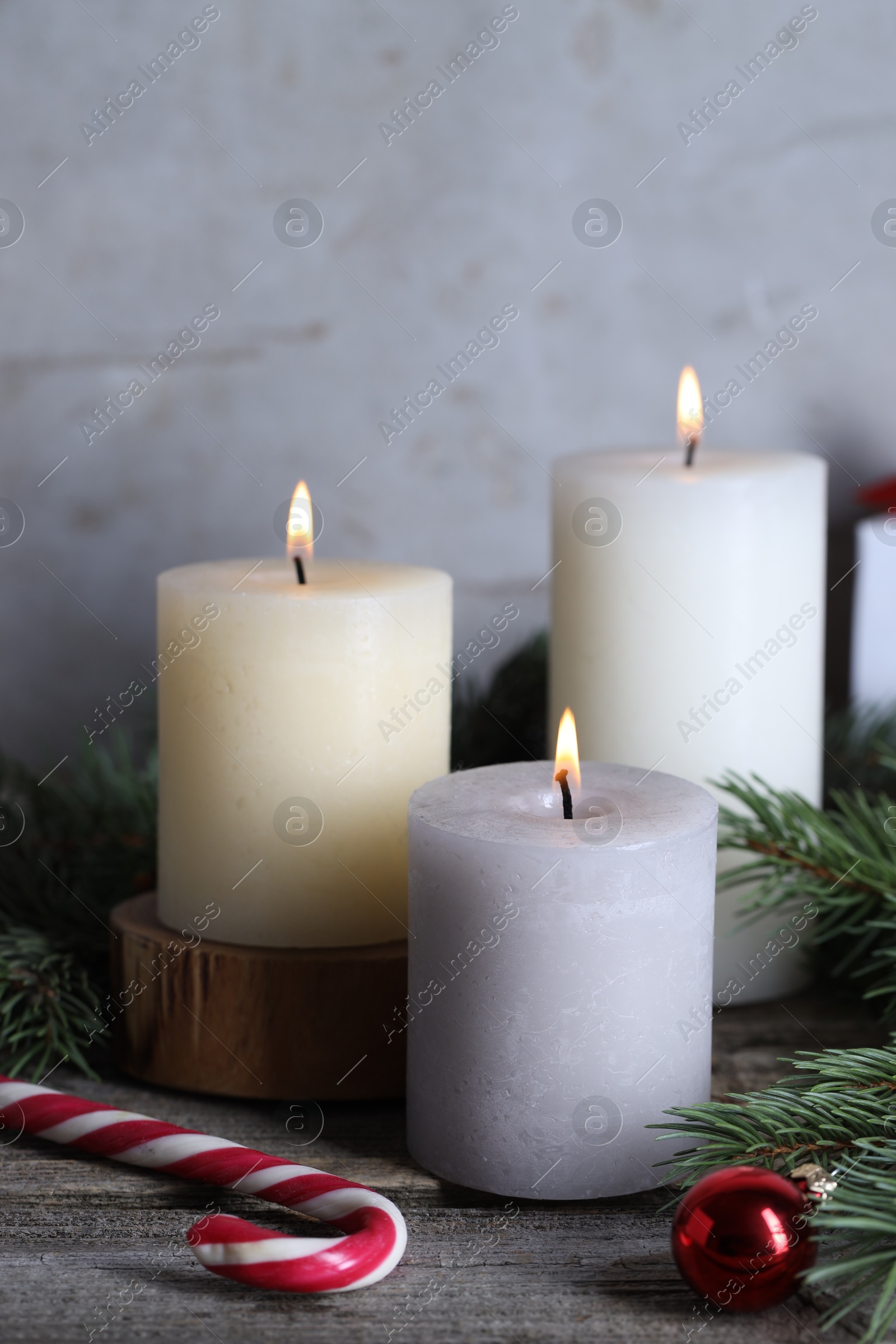 Photo of Burning candles, Christmas decor and fir tree branches on wooden table, closeup