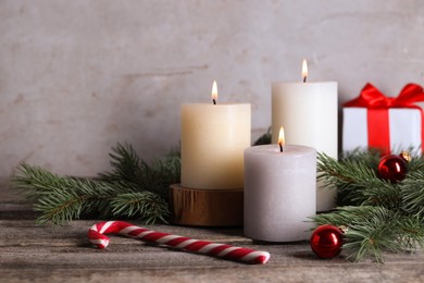 Photo of Burning candles, Christmas decor and fir tree branches on wooden table, closeup