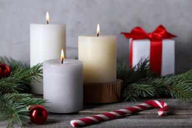 Photo of Burning candles, Christmas decor and fir tree branches on wooden table, closeup