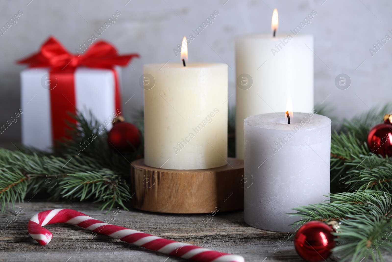 Photo of Burning candles, Christmas decor and fir tree branches on wooden table, closeup