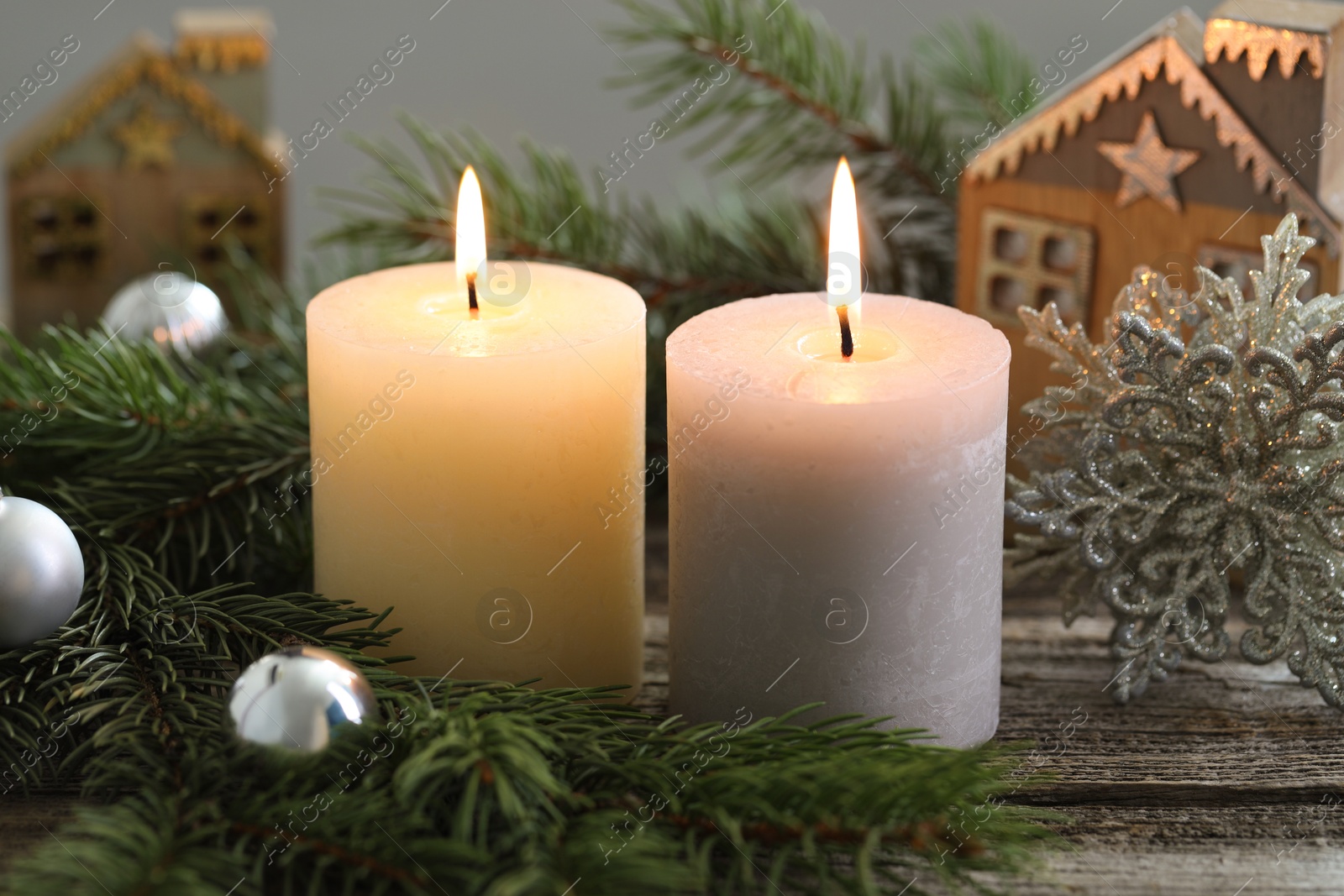 Photo of Burning candles, baubles and fir tree branches on wooden table, closeup