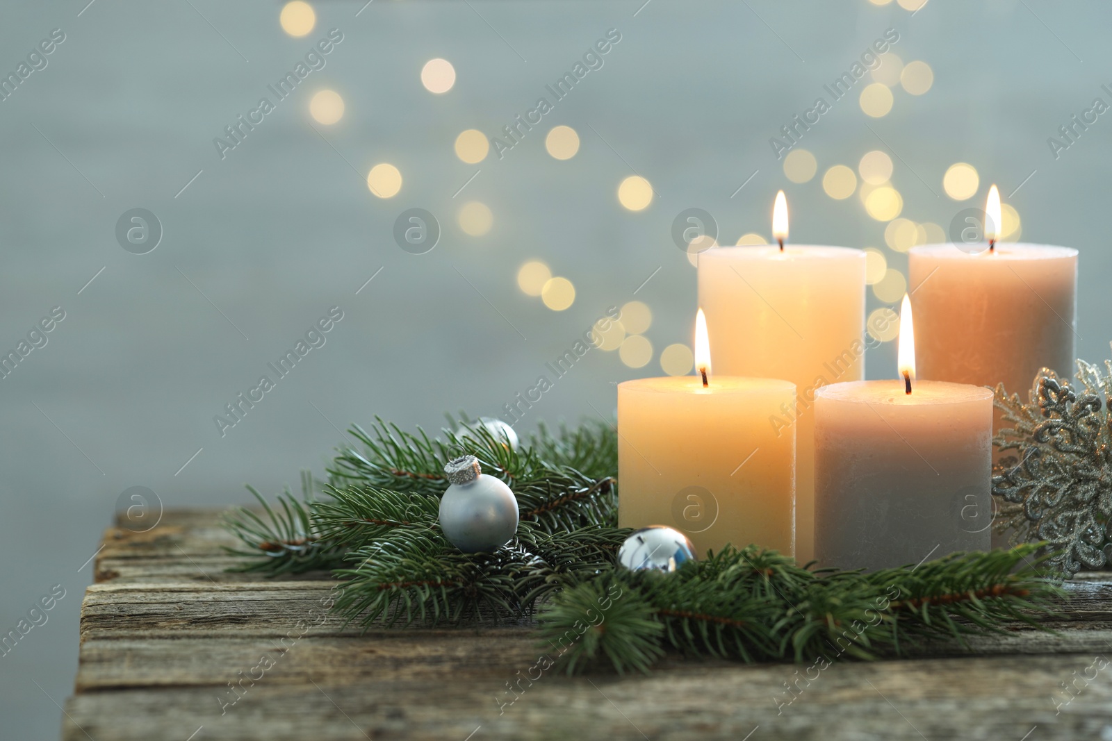 Photo of Burning candles, baubles and fir tree branches on wooden table, closeup. Space for text