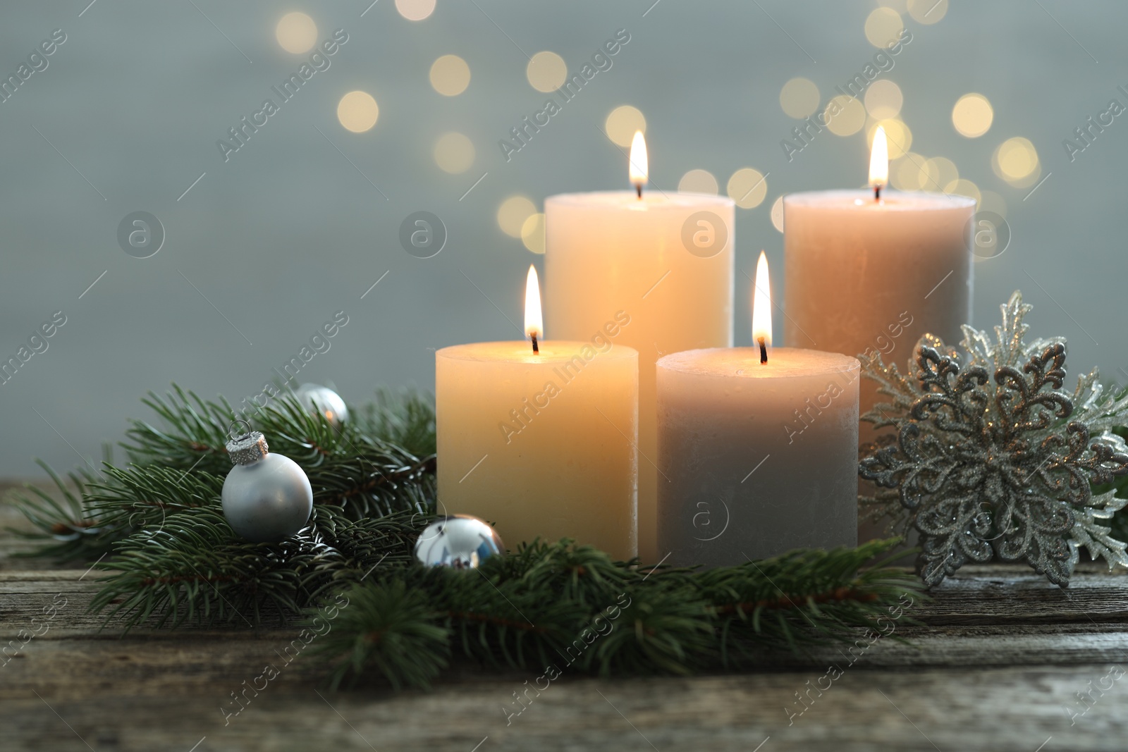 Photo of Burning candles, baubles and fir tree branches on wooden table, closeup