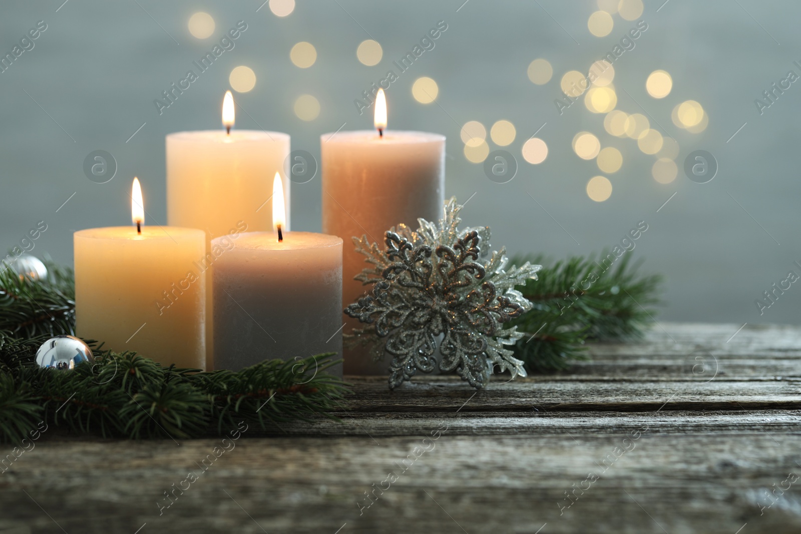 Photo of Burning candles, baubles and fir tree branches on wooden table, closeup. Space for text