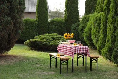 Fresh fruits, pie and vase with sunflowers on table in garden, space for text